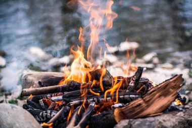 Şiddetli bir rüzgarla nehir kıyısında kamp ateşi