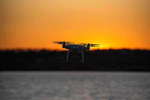 Drone flies over the lake at sunset time
