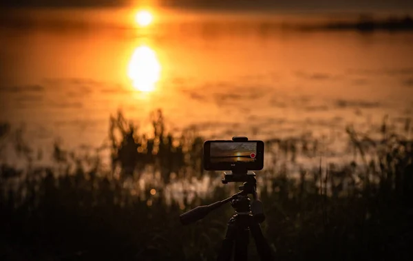 The smartphone shoots a sunset video on the lake