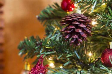 Yeşil Noel ağacı süslenmiş ışıklar, çanlar, renkli toplar, yıldızlar ve çam kozalakları