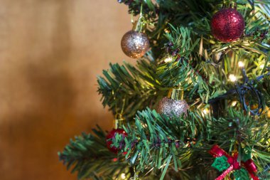 Yeşil Noel ağacı süslenmiş ışıklar, çanlar, renkli toplar, yıldızlar ve çam kozalakları