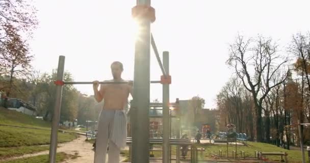 Young man is doing pull ups on the bar in good weather 4K — Stock Video