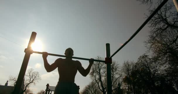 Giovane uomo sta facendo pull up sul bar con il bel tempo 4K — Video Stock