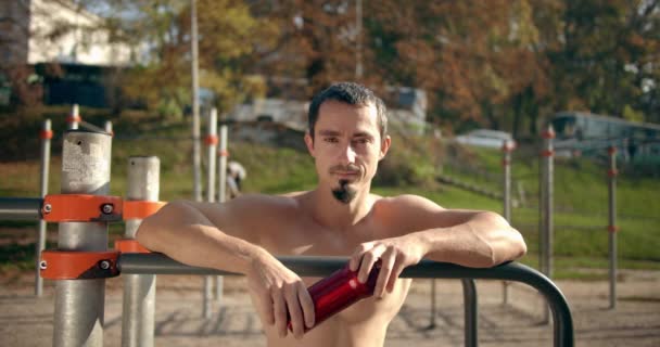 Un hombre está sonriendo y de pie en los bares con un agitador en la mano en el clima soleado 4K — Vídeo de stock