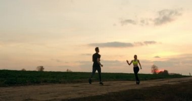 Bir adam ve bir kız, sonbahar havasında koşarken el çırpıyorlar.