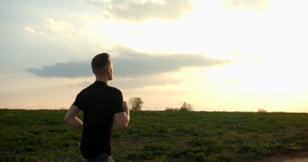 Νεαρός τρέχει εκτός δρόμου το ηλιοβασίλεμα το φθινόπωρο 4K καιρό — Αρχείο Βίντεο