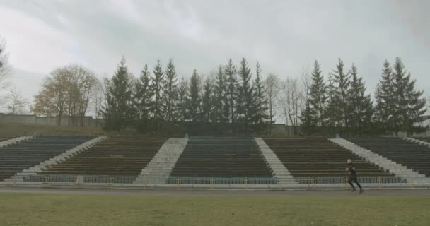 Sportowiec biegnie wokół stadionu rano w mglistej jesiennej pogodzie 4K — Wideo stockowe