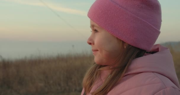 Une petite fille court et tient un cerf-volant en l'air et sourit. Le soleil au-dessus du brouillard. 4k — Video