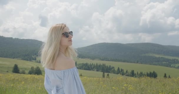 Krásná dívka se obrací ke kameře. Usmívající se dívka. Slunečný den. Krásné hory v pozadí 4K — Stock video