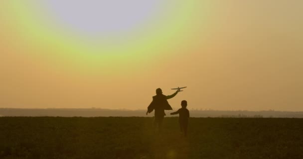 Jongens spelen met een speelgoedvliegtuig en rennen. Zonsondergang. 4K — Stockvideo