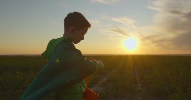 Хлопчик стоїть на полі і ремонтує літак. Захід сонця. 4-кілометровий — стокове відео