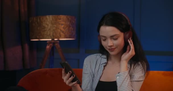 A menina está ouvindo música em fones de ouvido e descansando à noite. 4K — Vídeo de Stock