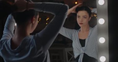 Güzel bir kız aynanın önünde saçını düzleştiriyor ve kendine hayran. 4K
