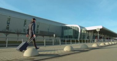 Bavullu adam havaalanına gidiyor. Uçakla git. Güneşli bir hava. 4K