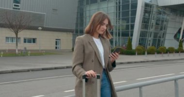 Genç bir kız mesaj atıyor ve gülümsüyor. Uçakla git. Güneşli bir hava. 4K
