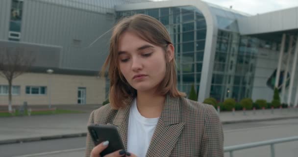 Una joven está enviando mensajes de texto y sonriendo. Viajar en avión. Clima soleado. 4K — Vídeos de Stock