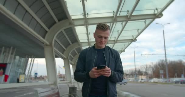 男は空港を通過し、輸送を探しているときにメッセージを入力しています。4K — ストック動画