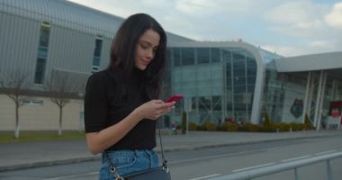 Güzel kız havaalanının yanında dururken gülümsüyor ve telefonda mesajlaşıyor. O, saçını düzleştiriyor. Uçakla git. 4K