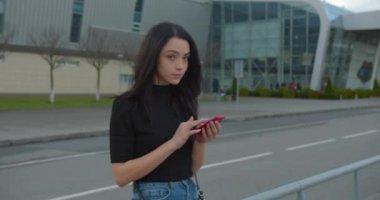 Kız gülümsüyor ve havaalanının yanında dururken telefonda mektuplaşıyor. 4K