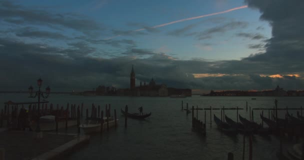 ゴンドラで港を出発し、夕日と船が背景を通過しています。イタリアのヴェネツィア。4K — ストック動画
