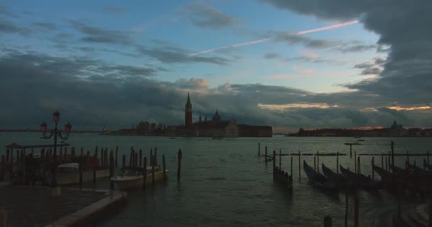 Timelapse del puerto para la góndola con puesta de sol y el movimiento de nubes y barcos en el fondo. El anochecer, la inclusión de luces. Venecia, Italia. 4K — Vídeo de stock