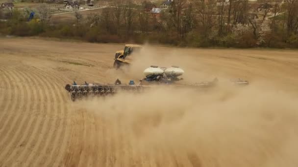 A disparar de um drone. Um trator está a cultivar a terra. Preparação para a sementeira. Tiroteio de perto. 4K — Vídeo de Stock