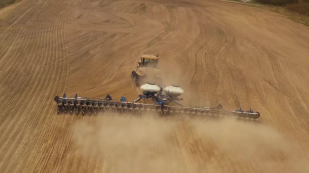 A disparar de um drone. Um trator está a cultivar a terra. Preparação para a sementeira. Tiroteio de perto. 4K — Vídeo de Stock