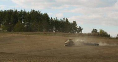 Bir İHA 'dan ateş etmek. Bir traktör toprağı işliyor. Ekmek için hazırlık. 4K