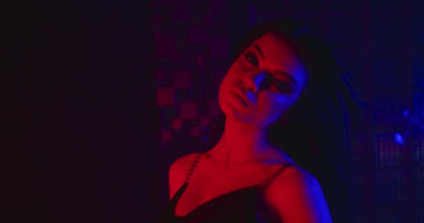 Das Mädchen posiert sexuell, spielt mit ihren Haaren und blickt in die Kamera. Mode sieht aus. Blau-rotes Neon. 4k — Stockvideo