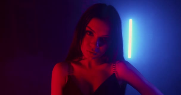 Ta dívka pózuje sexuálně a dívá se do kamery. Módní vzhled. Střílí v modrém a červeném neonu s kouřem. 4k — Stock video