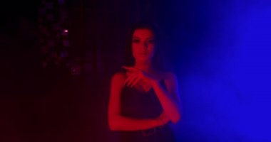 Güzel bir kız cinsel olarak parmağını dudaklarına dayıyor. Moda bakışı. Mavi ve kırmızı neon ışıklarla çekiliyor. 4k