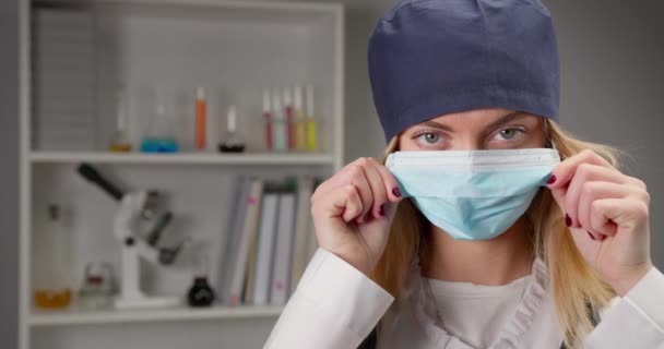 Bir sağlık çalışanı laboratuvarda koruyucu bir maske takıyor. 4k — Stok video