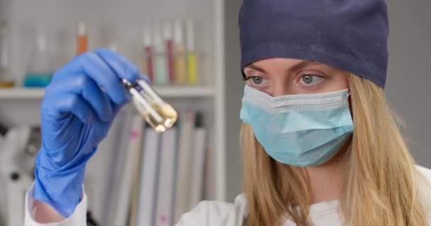 Een medisch medewerker roert het medicijn voor gebruik en kijkt dan naar de camera. Experimenten in het laboratorium. 4K — Stockvideo
