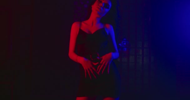 Das Mädchen läuft sexuell mit den Händen entlang der Taille und hebt sie bis zur Brust, und ihre Haare fliegen im Wind. Mode sieht aus. Blau-rotes Neon. 4k — Stockvideo