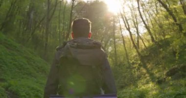 Arkadan ateş ediyorlar. Adam ormanın içinde yürüyor. Ormanda yürüyüş. 4K