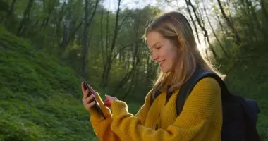 Kız akıllı telefondaki haritalara göz gezdiriyor. Ormanda yürüyüş. 4K