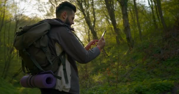 Ten chlap se dívá na mapy na smartphonu. Pěší túra v lese. 4K — Stock video