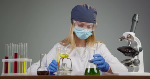 En labbarbetare blandar flera grundämnen i en kolv. Experiment i laboratoriet. 4K — Stockvideo