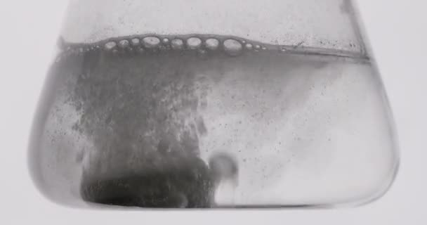 Närbild skytte. En reagens kastas i en kolv med vatten. Experiment i laboratoriet. 4K — Stockvideo