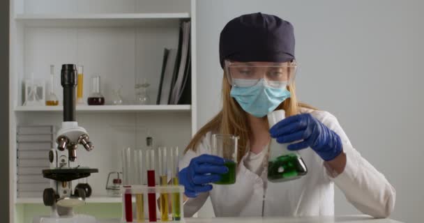 Un trabajador de laboratorio está mezclando componentes en un matraz y observando su reacción. Experimentos en el laboratorio. 4K — Vídeos de Stock