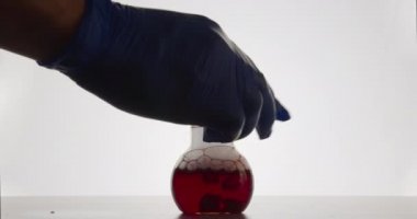 Laboratuvar asistanı kimyasal reaksiyonun gerçekleştiği şişeyi koyuyor. 4k