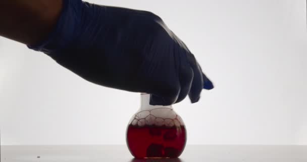 L'assistant de laboratoire met la fiole dans laquelle la réaction chimique a lieu. 4k 