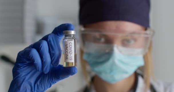 Close-up shot. A lab worker in a protective suit is showing a test tube with the COVID-19 vaccine. Experiments in the laboratory. 4K — Stock Video