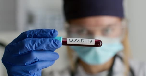 至近距離から撃たれた。保護スーツの研究室の労働者は、 COVID-19で試験管を示しています。実験室での実験。4K — ストック動画