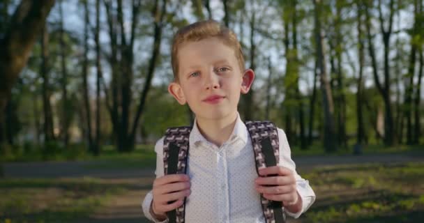 Närbild porträtt. Pojken justerar sin ryggsäck. 4k — Stockvideo