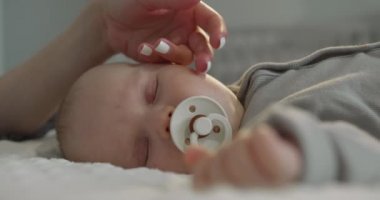 Yakın plan çekim. - Bebek uyuyor. Anne nazikçe eliyle yüzünü okşuyordu. 4K