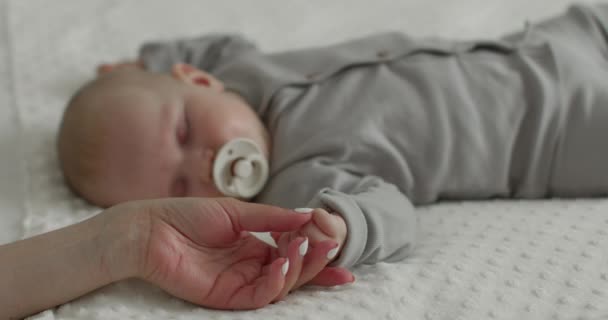 Nahaufnahme. Baby schläft und lutscht Schnuller. Die Mutterhand hält die Babys an der Hand. 4k — Stockvideo