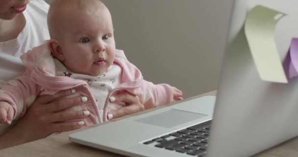 Close-up shooting. The mother with the baby is working on a laptop. 4K — Stock Video