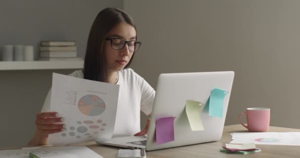 En pige med briller arbejder på en bærbar computer og ser på diagrammet. 4K – Stock-video