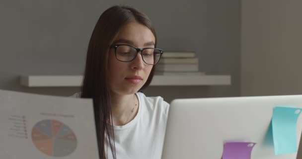 Tiroteio de perto. Uma menina com óculos está trabalhando em um laptop e olhando para o diagrama. 4K — Vídeo de Stock
